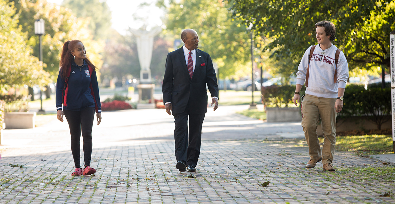 President Antoine M. Garibaldi walks with students on Detroit Mercy's McNichols Campus.