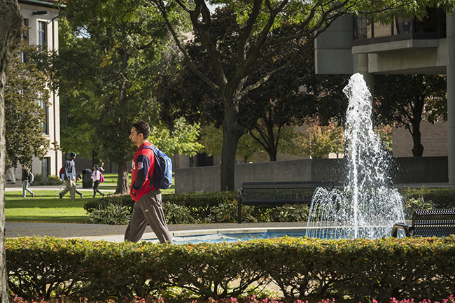 Student walking by fountain.