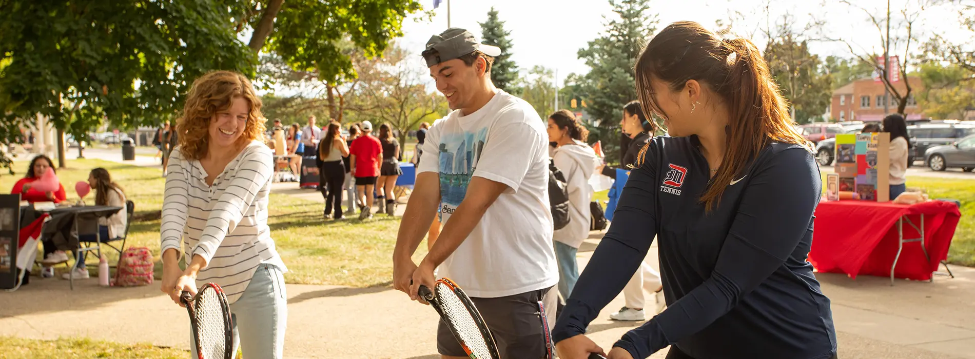 three students hold tennis rackets