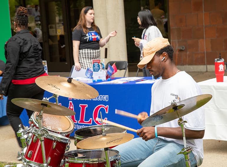 a student playing a drum set near the fountain