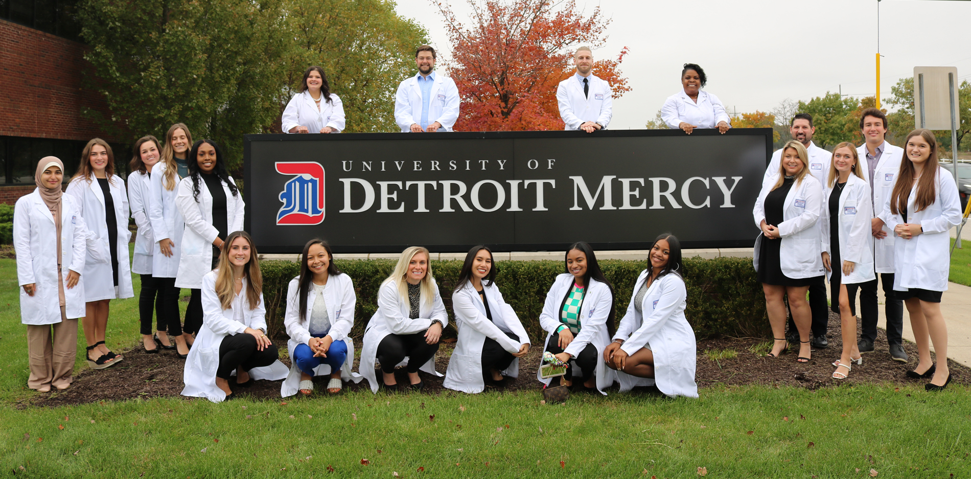 first cohort class of meagn program wearing their white coats outside of the novi campus