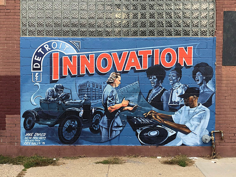 A mural painting on a brick wall depicts Detroit Innovation, with various Detroit-related paintings.