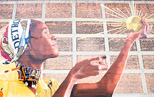 A mural on a brick wall in Detroit depicts a person holding the Spirit of Detroit.