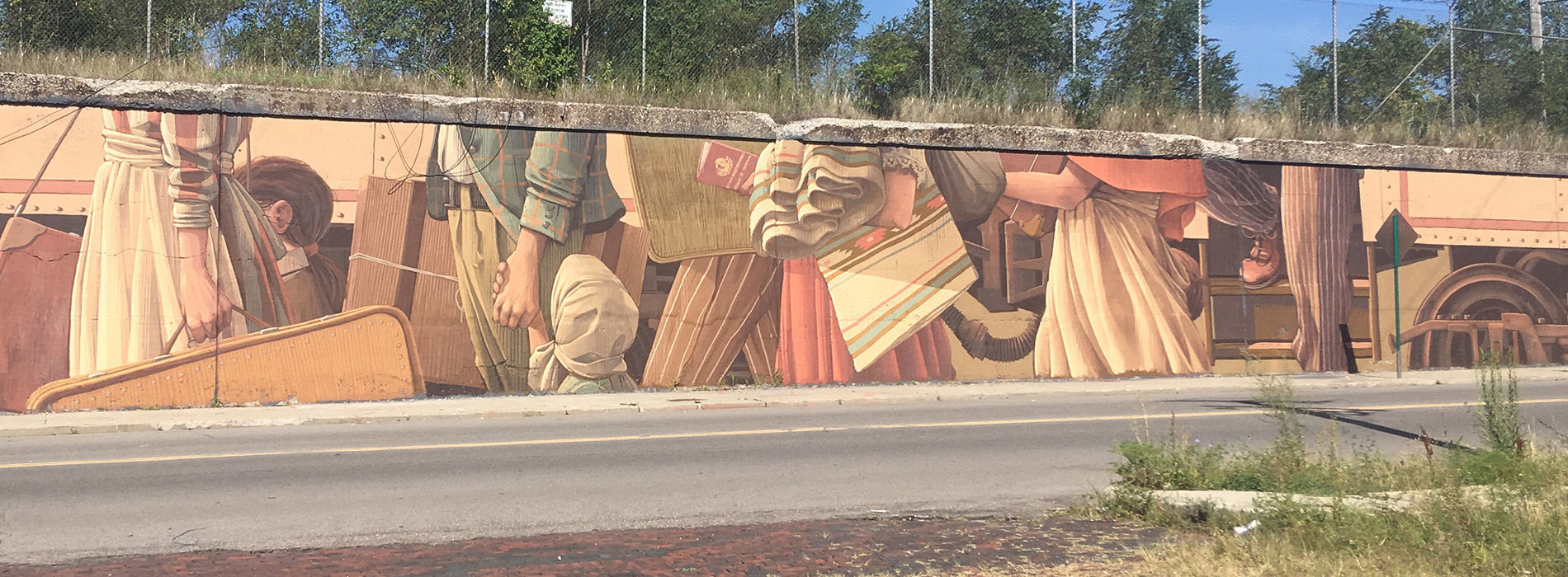 A mural on a long wall depicts passengers getting on a train, in Detroit.