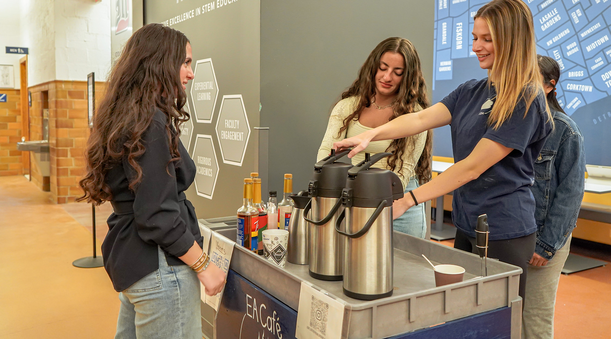 Four students stand around the EA Cafe coffee cart inside of the Engineering Building.