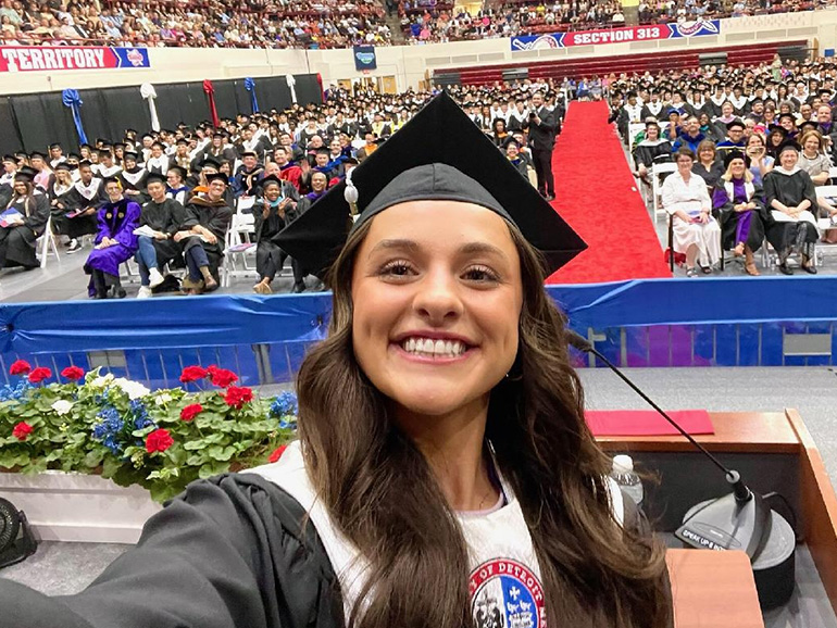 Kara Wolfbauer takes a selfie from the Calihan Hall stage during Commencement with hundreds of people behind her.