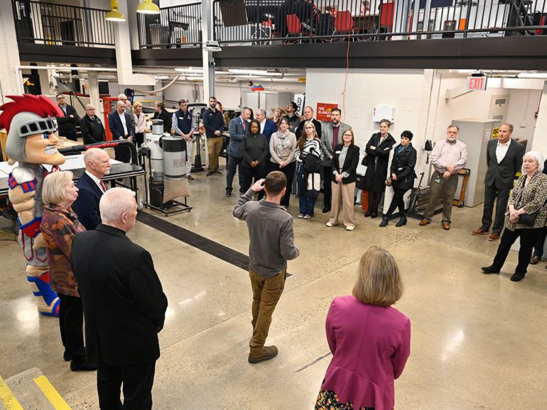 People stand and listen to someone talking inside of the annex.