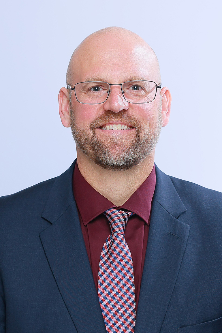 A head shot photo of Nicholas Schroeck in suit and tie