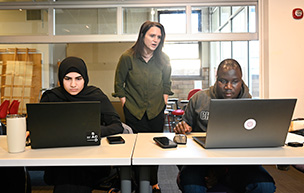 A professor overlooks students in an Architecture class while providing a helping hand.