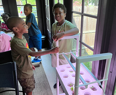 Detroit children stand near one of the hydroponic systems at Brilliant Detroit.