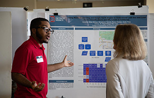 A student presents his research to someone at the Celebration of Scholarly Achievement event.