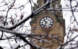 A photo of the McNichols Campus clocktower during the winter and through tree branches.