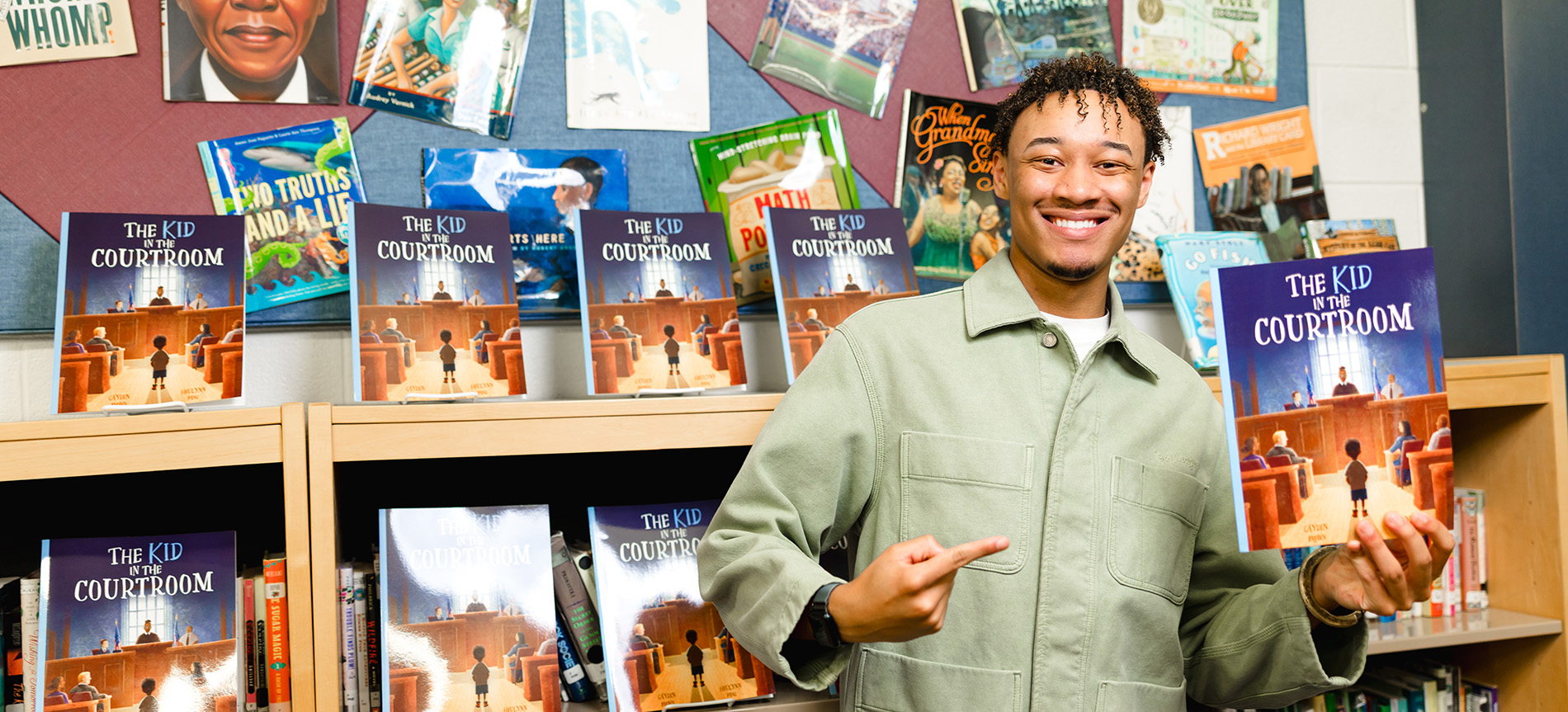 Cayden Brown holds his book "The Kid in the Courtroom" in a Library.
