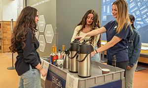 A student orders a beverage from the EA Cafe, as students work behind the coffee cart to operate the business.