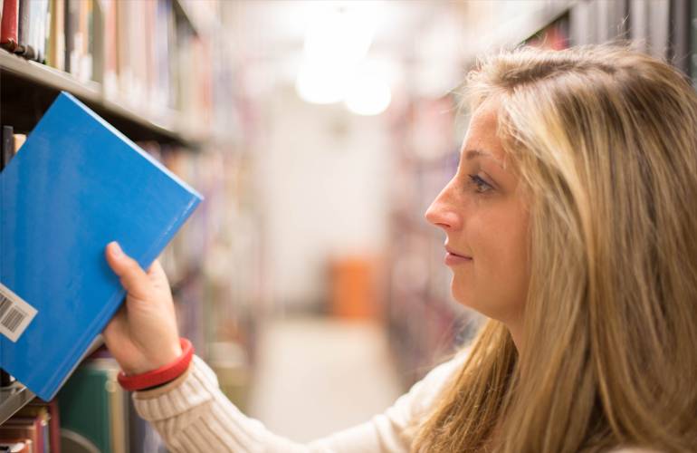 Girl in library picking a book