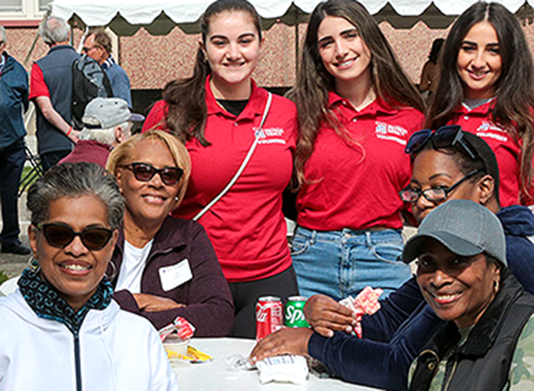 students and alumni at a table at homecoming