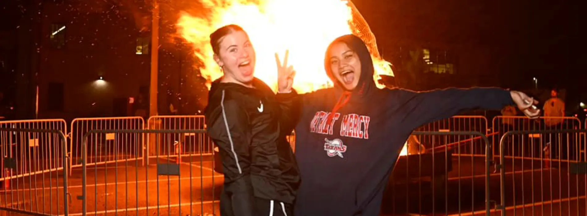 two girls waving  in front of a bonfire