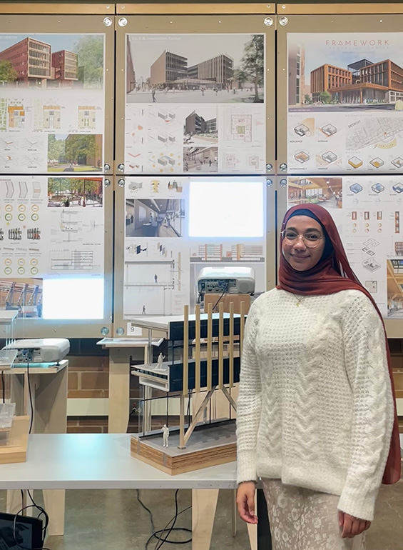 Zaynab Alhisnawi stands next to one of her design posters.