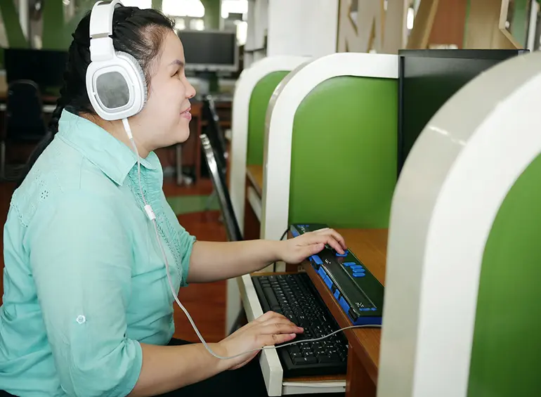 a blind asian woman working with a braille keyboard