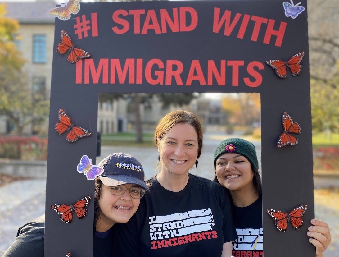 students holding an "I stand with immigrants" frame around themselves