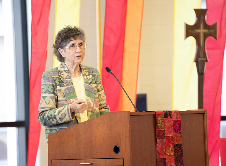 An image of Marilyn Lacey, RSM, standing at podium delivering a speech